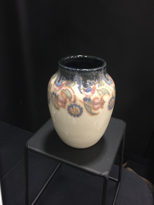 white and blue pottery vase with floral motif on black stand